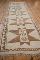 Angled perspective view down a distressed Kurd runner, showing its textural weave and starburst medallions.