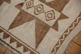 Corner of a distressed Kurd rug with a textured pile, starburst motif, and short ivory fringe.