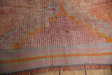 Distressed vintage Kurd rug with faded coral pile, striped flatweave, and fringe.