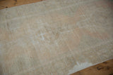 Distressed abrashed field of a vintage Oushak rug, showing faded ivory and pale blush.