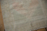 Close-up of vintage distressed Oushak runner, showing worn pile, side selvage, and fringe.