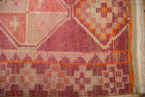 Textured geometric pattern of a distressed vintage Kurd runner in rose, fuchsia, and ivory, with secured side.