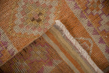 Distressed pile of a vintage Kurd runner, showing faded orange, fuchsia, ivory tones and fringe.
