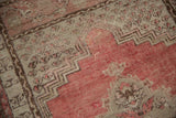 Distressed Kula rug detail: worn dusty cherry red, beige fields, and stepped brown border.
