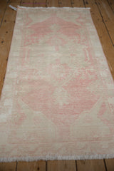 Distressed vintage Oushak rug runner, revealing its faded blush and ivory decorative pattern.