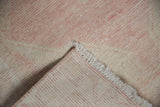 Reverse and worn pile of vintage distressed Oushak rug with blush tones and fringe.