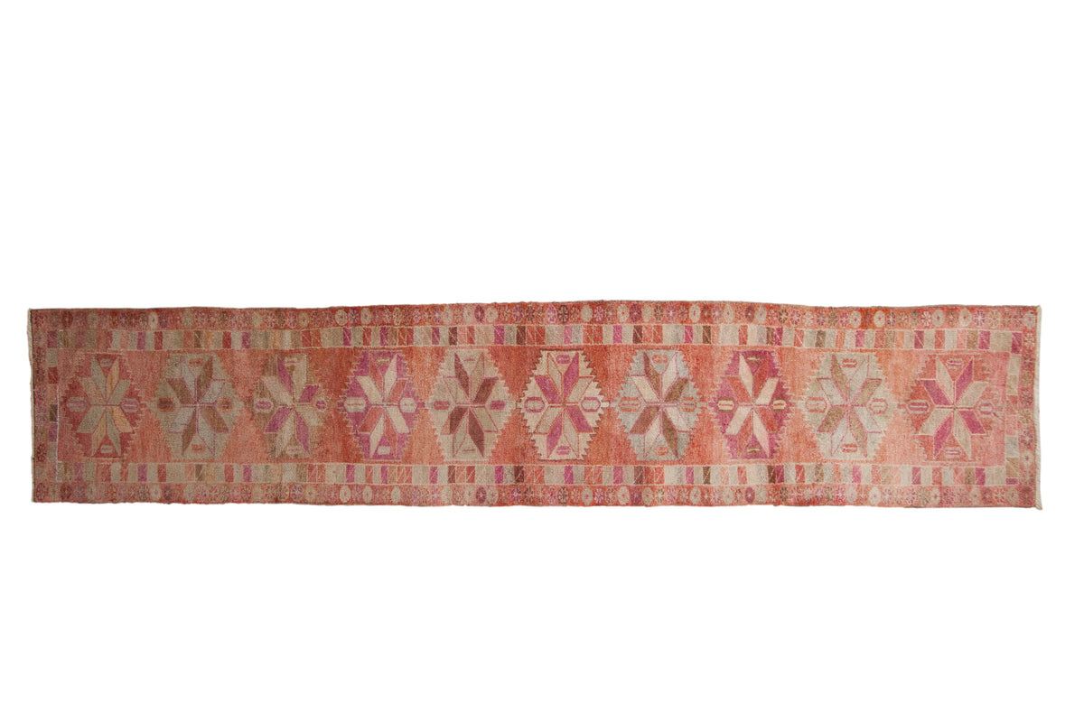 Vintage distressed Kurd rug runner with geometric starburst medallions in hues of pink grapefruit red and ivory.