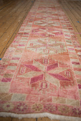 Low-angle view of a distressed Kurd runner showing its repeating pink starburst medallions.