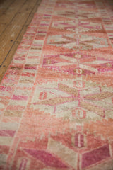 A low angle view along the vintage Kurd runner showing its short pile and abrashed pink hues.