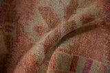 A soft fold in the vintage Kurd rug showing its even, short pile texture in tones of pink and ivory.