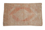 Distressed Oushak rug with concentric medallions, floral finials, dusty rose, ivory, and pale blue.