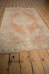 Distressed Oushak corner with arabesque spandrel, dusty rose, beige, and pale blue.