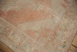 Distressed Oushak rug corner showing stepped pattern in dusty rose, ivory, and pale blue.