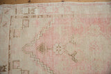Distressed pink, ivory, and coffee Oushak rug showing geometric and floral patterns.