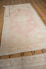 Distressed vintage Oushak rug texture with faded pink and ivory tones.