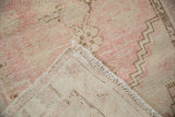 Distressed vintage Oushak rug showing faded pink pile, ivory fringe, and reverse.