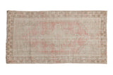 Distressed vintage Oushak rug, central pink medallion, and faded ivory geometric designs.