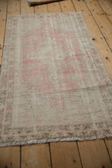 Close-up of worn pile showing faded pink geometric blossoms and foundation of a distressed Oushak rug.