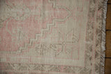 Distressed Oushak rug pile showing exposed foundation, wear across knot heads, pink and oxidized silver.