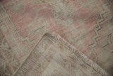 Distressed pink and ivory Oushak rug pile texture with fringe and woven foundation.