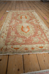 Corner of distressed Oushak runner, mostly even wear, raspberry, ivory, tangerine floral motifs.