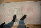Worn, low-pile texture on a vintage Oushak runner in soft pink and dusty green.