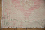 Hand-knotted texture and low pile on the corner of a distressed Oushak with short ivory fringe.