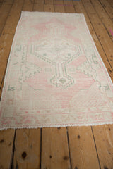 Angled view of a distressed Oushak runner showing its soft pink, ivory, and green geometric pattern.
