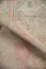 Rolled view of a distressed Oushak runner reveals the low hand-knotted pile and worn texture.