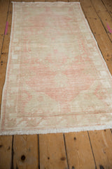 Distressed Oushak runner texture, showing faded pink and beige with mostly even wear to knot heads.
