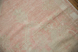 Distressed vintage Oushak rug texture with soft pink and beige pile, showing visible wear.