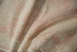 Decorative distressed texture of the Oushak rug, featuring worn pinks and beige tones with visible foundation.