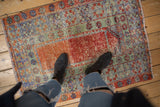 Distressed Oushak rug corner featuring faded floral border, visible pile wear, and secured fringe.