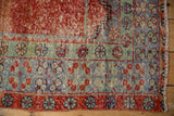Patinaed texture and blossomed floral border motifs in terracotta, jade, and blue on the vintage Oushak rug.