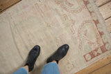 Distressed vintage Oushak rug detail with ivory, pale green, and chestnut floral patterns, showing worn pile.