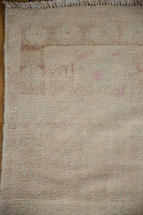 Distressed ivory Oushak rug pile with subtle pink hues and worn, textural surface.
