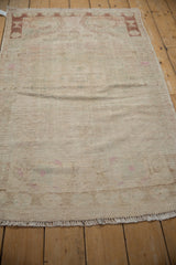 Distressed Oushak rug texture with visible knot heads, faded ivory, and subtle blush tones.