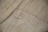 Vintage distressed Oushak rug's reverse, fringe, and worn ivory pile texture.