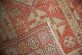 Distressed Kurd rug detail: pale red and ivory geometric pile, showing reverse and fringe.