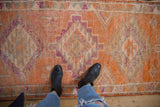 Distressed vintage Kurd runner with tangerine, purple, ivory, and oxidized silver geometric design.