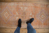 Distressed vintage Kurd runner displaying geometric patterns and worn pile in tangerine, ivory, copper, purple tones.