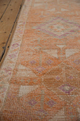 Distressed Kurd runner showing tangerine and ivory geometric border with purple pattern details.