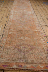 Textured pile and geometric border of the distressed Kurd runner in tangerine, ivory, and purple.