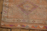 Distressed Kurd runner corner with worn tangerine, ivory, purple pile, geometric border, fringe.