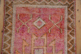 Textured pile of a vintage distressed Kurd runner with geometric ruby red, tangerine, brown patterns.
