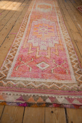 Distressed vintage Kurd runner, geometric starburst and arrow motifs in ruby red, tangerine, purple.