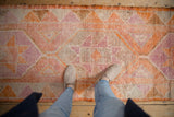Distressed vintage Kurd runner's texture, showing tangerine orange and soft purple starburst motifs.