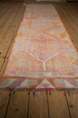 Distressed Kurd runner pile, highlighting pink and orange geometric patterns and colorful fringe.