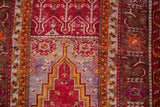 A close-up of the Ghiordes prayer design with cherry red plant motifs and saffron borders.