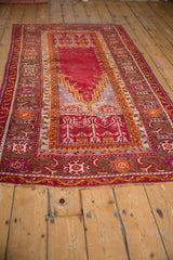 Hand-knotted texture on the geometric borders of a vintage Ghiordes rug in red, yellow, and brown.